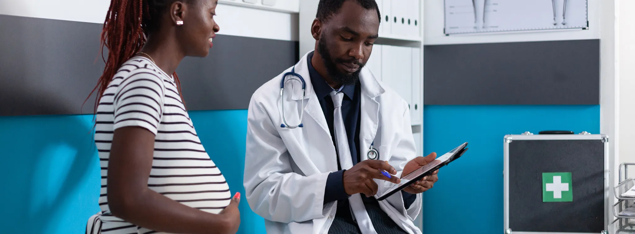 pregnant woman in a hospital looking over a medical form with a doctor