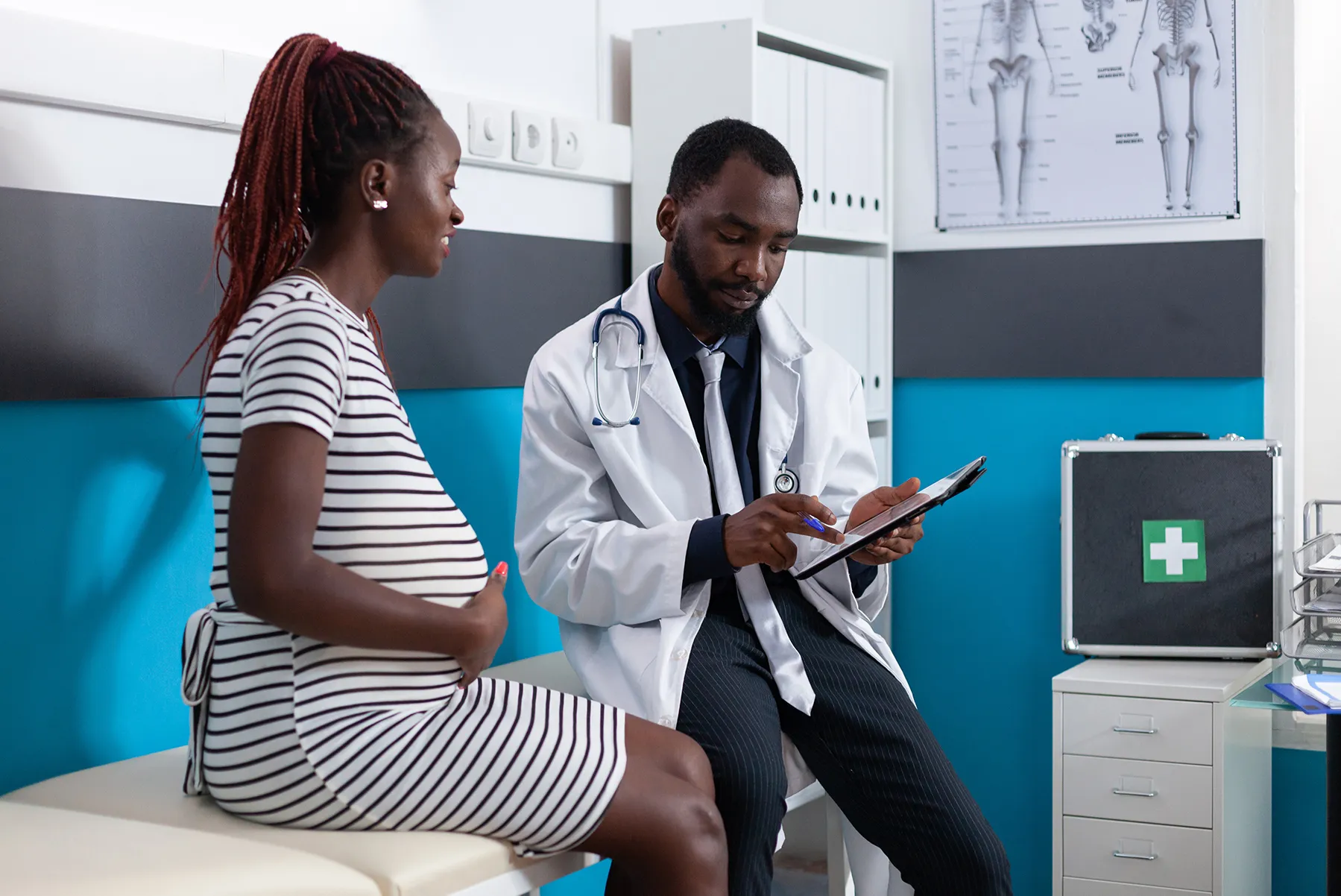pregnant woman in a hospital looking over a medical form with a doctor